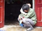 ông Lê Văn Tuấn ôm đứa cháu trai, bật khóc khi không có tin tức gì về người con trai Lê Văn Hà (ảnh: Getty Images)