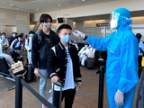 Nhân viên y tế kiểm tra nhiệt độ của hành khách ở sân bay (Ảnh - BYT)