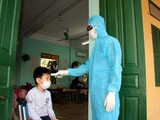 Nhân viên y tế kiểm tra nhiệt độ cho trẻ (Ảnh - HY)
