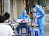 Nhân viên y tế lấy mẫu xét nghiệm COVID-19 cho người dân ở khu vực bên ngoài Bệnh viện Hữu nghị Việt Đức (Ảnh - Minh Nhân)