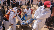 Nhân viên y tế Palestine kéo các thi thể bị chôn vùi từ một ngôi mộ tập thể tại khu liên hợp Y tế Nasser ở Khan Younis, Gaza vào ngày 21/4 (Ảnh: Getty)