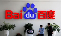 Khách giao dịch tương tác với robot AI của Baidu gần logo công ty tại trụ sở ở Bắc Kinh, Trung Quốc ngày 23/4/2021. Reuters