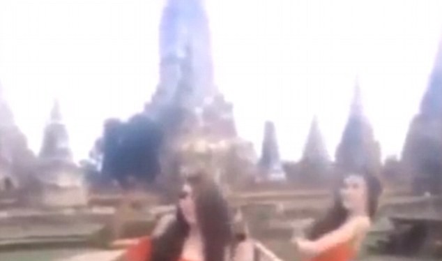 Hai phụ nữ mặc váy cam ngắn cũn nhảy nhót trước đền thiêng