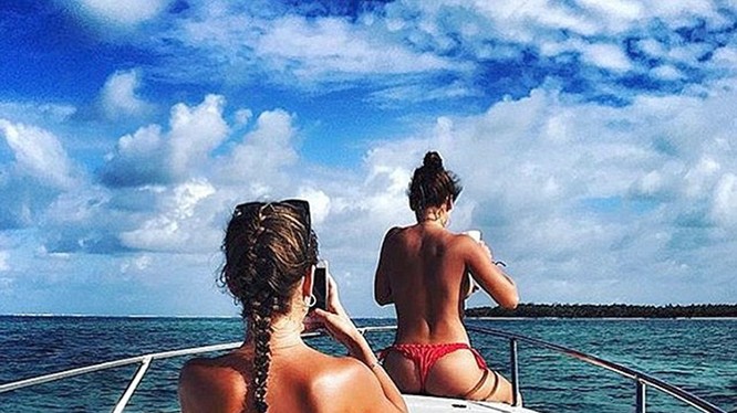 Hai cô gái Nga chụp ảnh trong bộ bikini của họ trong khi trên một thuyền buồm du thuyền trên đại dương trong một kỳ nghỉ nhiệt đới