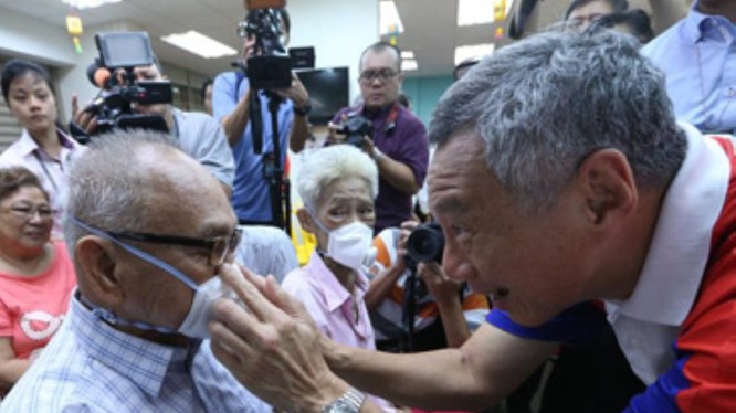 Do dịch bệnh bùng phát trở lại, Singapore ban hành lệnh bắt buộc người ra đường phải đeo khẩu trang. Trong ảnh: Thủ tướng Lý Hiển Long đeo khẩu trang cho người dân (Ảnh: Guancha).
