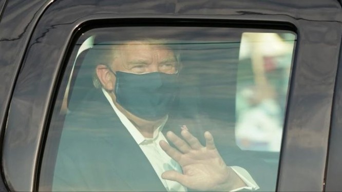 Ông Trump ngồi trên xe vẫy chào những người biểu tình ủng hộ sau cửa kính (Ảnh: The Australian).