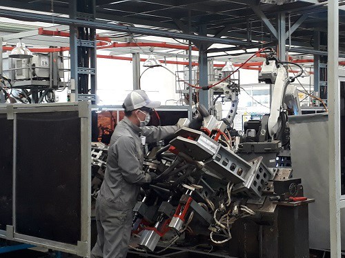 Công nhân Công ty VPIC thực hiện ráp phần khung sườn chiếc xe máy Ducati lên khuôn, các việc còn lại sẽ do robot thực hiện. Mỗi công nhân sẽ phụ trách 2 robot. Ảnh: Hà Thế An.