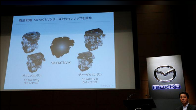 Chủ tịch hãng Mazda Masamichi Kogai bên cạnh màn hình giới thiệu động cơ mới tại cuộc họp báo ở Tokyo ngày 8/8. Ảnh Reuters