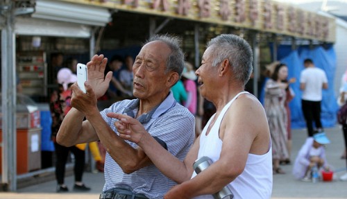 Hai người cao niên đang sử dụng điện thoại di động ở tỉnh Sơn Đông, tháng 5/2017. Ảnh: VCG.