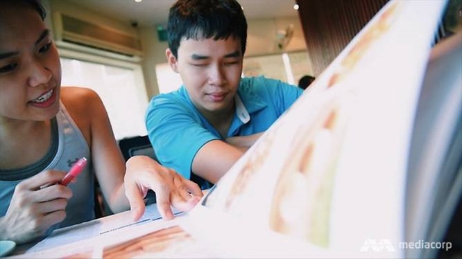 Bạn bè đang giúp anh đọc bản thực đơn trong nhà hàng. Ảnh: ChannelNewsAsia