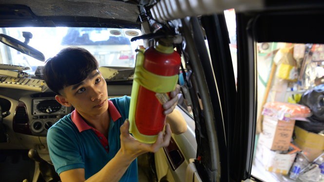 Nhân viên cửa hàng bán bình chữa cháy tại TP.HCM lắp đặt bình chữa cháy trên ôtô của khách hàng - Ảnh: Hữu Khoa