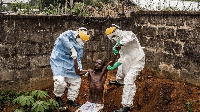 Bức ảnh này được thực hiện bởi Pete Muller, ghi lại người đàn ông nhiễm vi rút Ebola ở Freetown, Sierra Leone điên cuồng hoảng loạn cố thoát khỏi sự cô lập ở Trung tâm điều trị Hastings Ebola. Anh ta đã bị các nhân viên giữ và đưa quay trở lại trung tâm t
