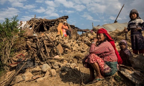 Người dân ngồi trước ngôi nhà bị động đất phá hủy ở Kathmandu. Ảnh: EPA