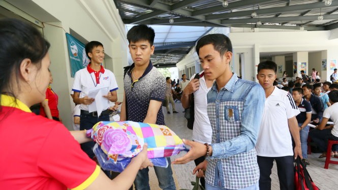 Thí sinh tỉnh Bình Thuận được sinh viên tình nguyện phát mền gối để vào KTX nghỉ miễn phí tại cụm thi Trường ĐH Tôn Đức Thắng sáng 29-6 - Ảnh: Như Hùng