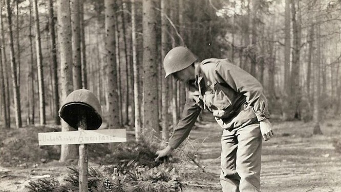 Một lính Mỹ đặt các cành thông lên mộ của lính Mỹ vô danh, bị quân Đức chôn trước khi rút lui.