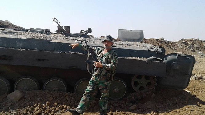 Một binh sĩ lực lượng đặc nhiệm Nga trên chiến trường Hama, bên một xe BMP của phiến quân bị hủy diệt - ảnh Masdar News