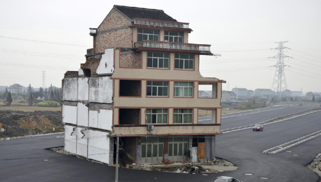 Một ngôi làng ở Chiết Giang bắt đầu di dời để phục vụ việc làm đường cao tốc. Tuy nhiên, đôi vợ chồng già kiên quyết không chuyển nhà. Giới bất động sản đặt tên cho những ngôi nhà kiểu này là “nhà đinh”. Ảnh: China Daily Infor.