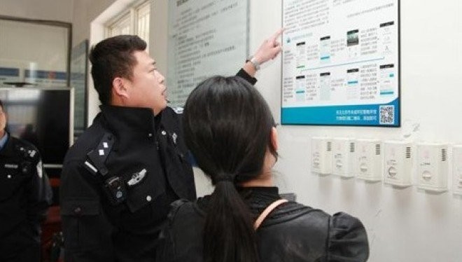 Một cảnh sát tại Bắc Kinh đang giải thích cho người nhà tù nhân về cách gửi tiền cho họ qua ứng dụng thanh toán Alipay.