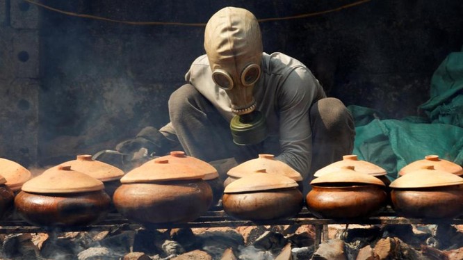 Anh Bùi Văn Cường đeo mặt nạ phòng độc để kho cá trắm (ảnh: Reuters)