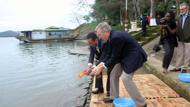 Đại sứ Mỹ Ted Osius và người bạn đời Clayton Bond cùng thực hiện nghi lễ thả cá chép trên sông Hương để tiễn đưa ông Công ông Táo về trời - Ảnh: Nguyên Linh