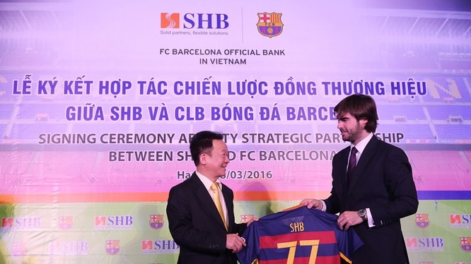 Ông Xavier Asensi - Giám đốc Điều hành khu vực Châu Á Thái Bình Dương CLB Barcelona (bên phải) tặng quà lưu niệm cho Ông Đỗ Quang Hiển - Chủ tịch HĐQT SHB, chiếc áo mang số 77 – là địa chỉ Trụ sở chính của SHB trên phố Trần Hưng Đạo