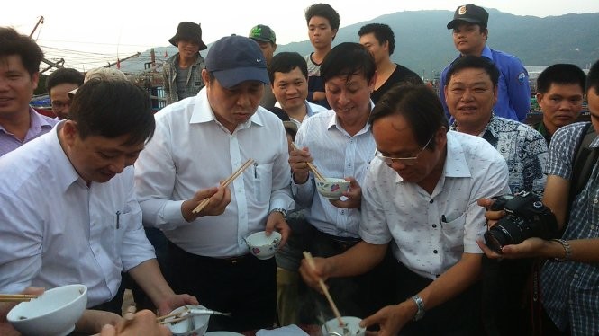 Chủ tịch UBND TP Đà Nẵng (đội mũ) ăn cá tại cảng cá Thọ Quang để dân an tâm - Ảnh: Đoàn Cường