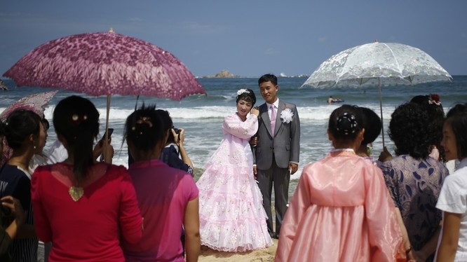 Cặp đôi mới cưới chụp ảnh trên bãi biển Sijung Ho trước sự chứng kiến của họ hàng và bạn bè.