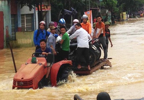 Tại Thanh Hóa, người dân dùng xe công nông để vận chuyển người và phương tiện qua đoạn ngập. Ảnh: L.H/ VnE