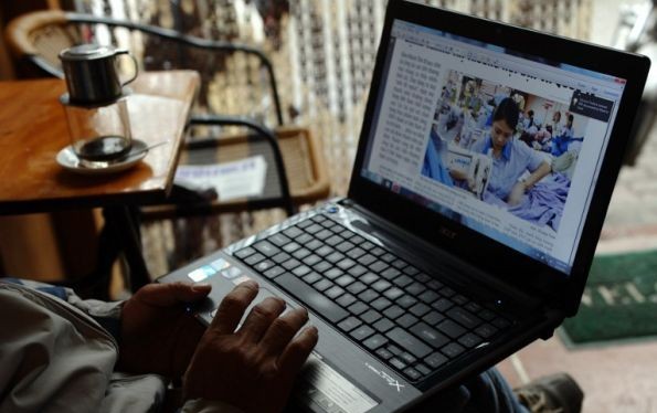 Một người đàn ông đang đọc tin trên mạng bằng laptop trong một quán cafe ở Hà Nội. Ảnh minh hoạ: AFP