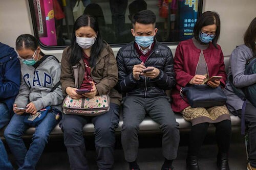 Người dùng smartphone đeo khẩu trang trên một chuyến tàu ở Hong Kong. Ảnh: AFP.