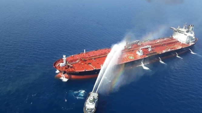 Một tàu của Iran cố gắng dập lửa cho con tàu bị tấn công trên vịnh Oman (Ảnh: Reuters)