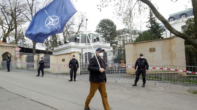 Một người đàn ông mang cờ NATO trước cửa Đại sứ quán Nga ở Praha, CH Séc (Ảnh: RT)