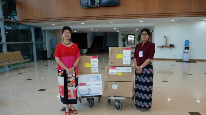 Đại sứ Singapore tại Myanmar - Vanessa Chan (trái) bàn giao các vật tư y tế tài trợ của Singapore cho Giám đốc Phòng thí nghiệm Y tế Quốc gia Myanmar - Htay Htay Tin, bao gồm 3.000 bộ xét nghiệm chẩn đoán và hai máy phản ứng chuỗi Polymerase (PCR) để xét 