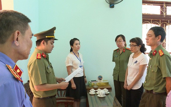 Bà Nguyễn Thị Hồng Nga, chuyên viên Phòng khảo thí và quản lý chất lượng Sở GD-ĐT Sơn La (mặc áo trắng bên phải), nghe tống đạt quyết định khởi tố bị can. 