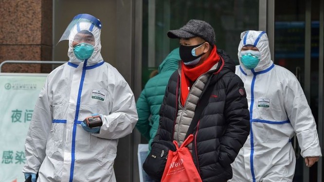 Nhân viên y tế cùng người dân đi bộ bên ngoài một bệnh viện ở Vũ Hán. Ảnh: AFP
