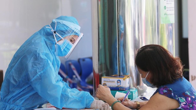 Nhân viên y tế hướng dẫn người dân khai báo y tế (Ảnh: Lê Bảo - Minh Thùy) 