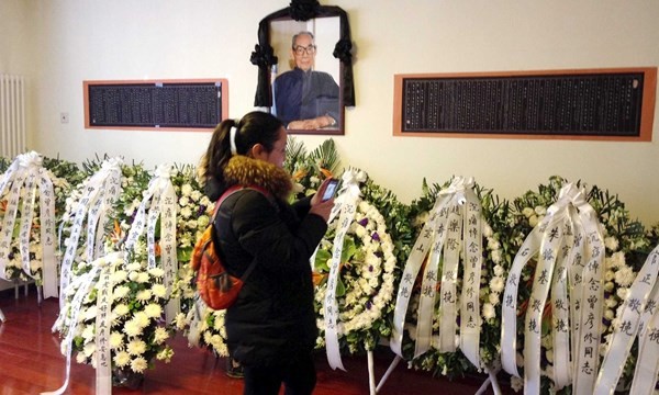 Một người phụ nữ chụp ảnh các vòng hoa của ông Tập và lãnh đạo CPC viếng tang ông Tăng Vân Tiếu