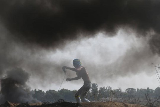 Người biểu tình Palestine ném gạch đá về phía binh lính Israel tại biên giới giữa Israel và Dải Gaza hôm 23-10 Ảnh: Reuters