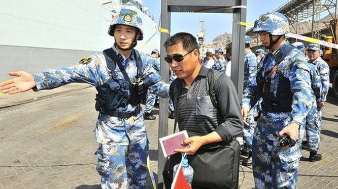 Công nhân Trung Quốc đi qua cửa kiểm tra an ninh trước khi lên tàu hải quân của nước này ở vịnh Aden. Ảnh: Reuters