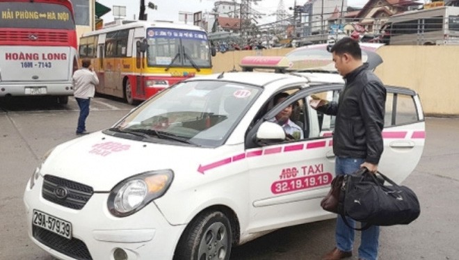 Giá cước taxi ở Hà Nội hiện thấp nhất cả nước (Một khách hàng thanh toán tiền taxi tại Bến xe Lương Yên, Hà Nội) - Ảnh: Dương Linh