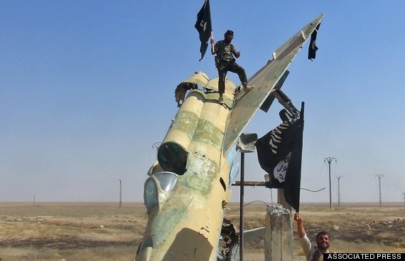 Phiến quân IS đứng trên xác một xác máy bay chiến đấu MiG 21 ở Iraq. (Nguồn: AP)