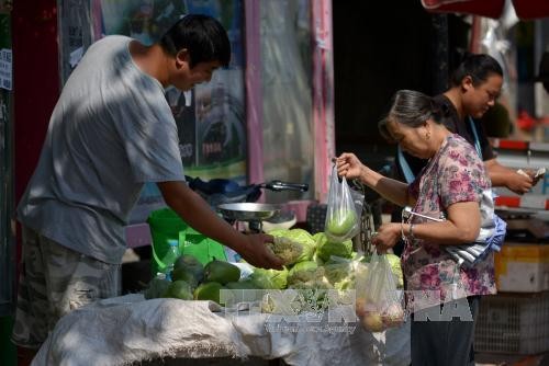 Người dân Trung Quốc mua hàng hóa tại chợ ở thủ đô Bắc Kinh. Ảnh: AFP/TTXVN