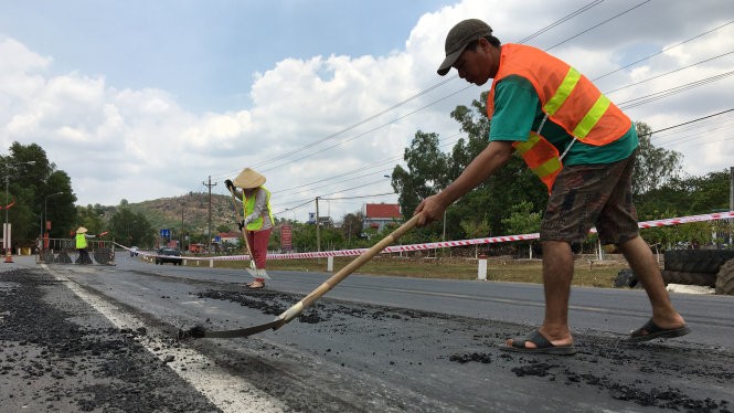 Chủ đầu tư Tổng công ty 319 cho nhân viên ra quốc lộ cào mặt nhựa đường bị trồi lên tại thị trấn Gia Ray, huyện Xuân Lộc, Đồng Nai - Ảnh: Hà Mi