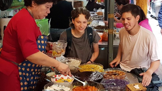 Du khách nước ngoài thích thú thưởng thức các món ăn tại ngõ Đồng Xuân