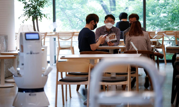 Khách hàng đang chờ đợi phục vụ tại một quán cà phê ở Hàn Quốc nơi robot pha chế sẽ thay thế hoàn toàn cho vai trò của con người. Ảnh: Reuters