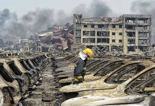 Lính cứu hỏa đi giữa các phương tiện bị phá hủy trong vụ nổ hôm 12/8. Ảnh: Reuters