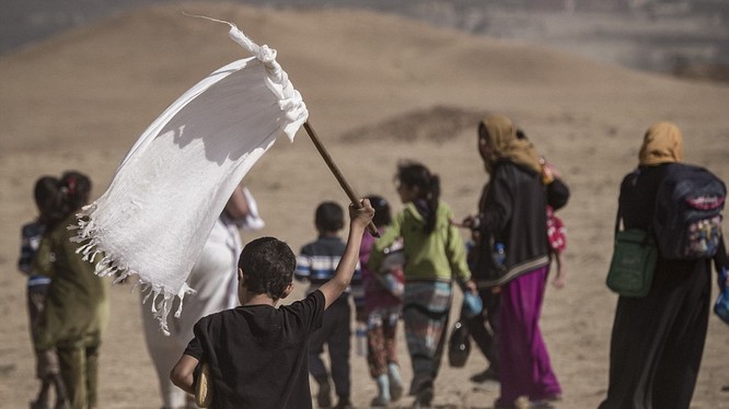 Một em nhỏ cầm cờ trắng trong dòng người chạy thoát khỏi Mosul