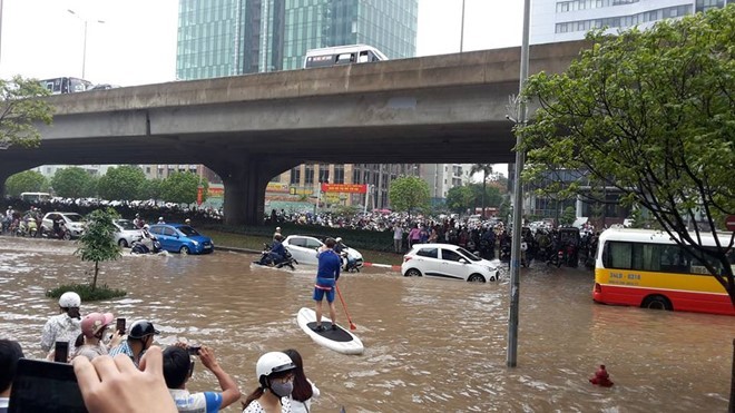 Người dân chèo thuyền trên đường vành đai 3 trong trận mưa ngày 25/5/2016