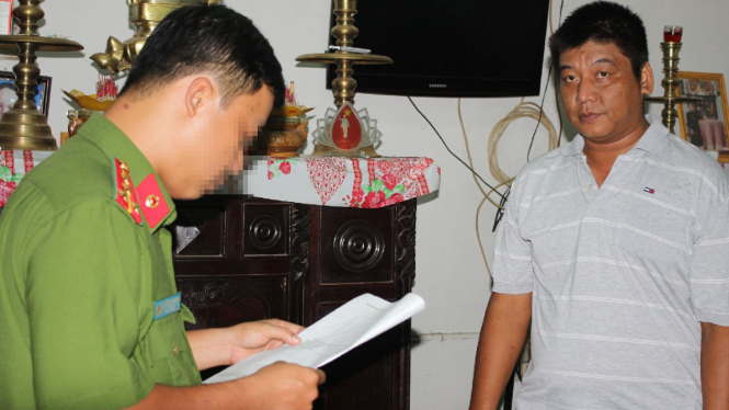 Công an đọc lệnh bắt tạm giam ông Bùi Văn Minh - Ảnh: Phan Tại/Tuổi trẻ