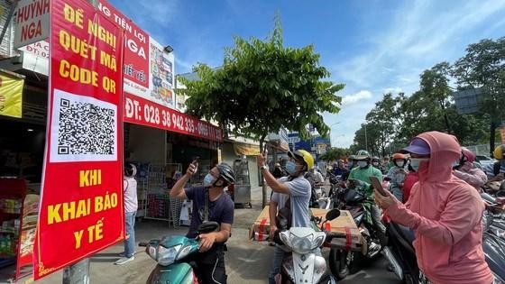 Người dân quét mã khai báo y tế trên điện thoại tại trạm kiểm soát trên đường Nguyễn Kiệm (Gò Vấp) ngày 7/6 (Ảnh: SGGP) 